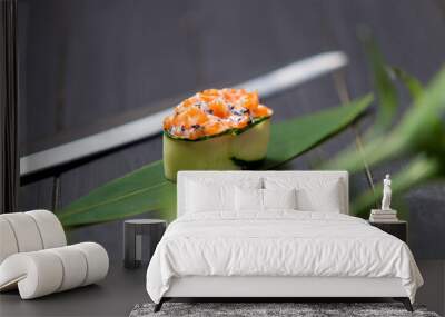 Gunkan Sake Green sushi with salmon, black tobiko caviar and cream cheese in cucumber served on bamboo leaf near Japanese knife. Pan Asian traditional dish on dark wooden background near green plant
 Wall mural