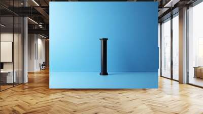 A black pillar stands in front of a blue wall Wall mural