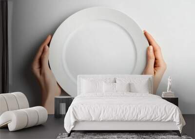 A person is holding a white plate with no food on it Wall mural