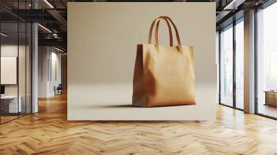 A tan purse with a brown handle sits on a white surface Wall mural