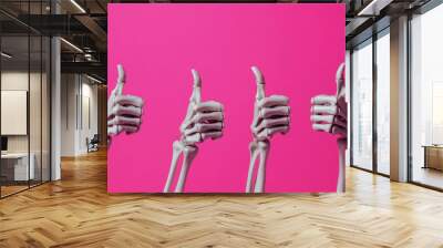 Four skeletal hands enthusiastically gesturing thumbs up in front of a bright pink backdrop, portraying a playful and quirky vibe Wall mural