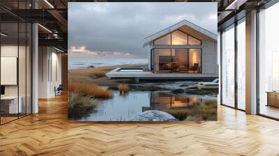 a modern, minimalist beach house surrounded by sand dunes and tall, windswept grasses. The house features large glass windows that allow for an unobstructed view of the beach and ocean Wall mural