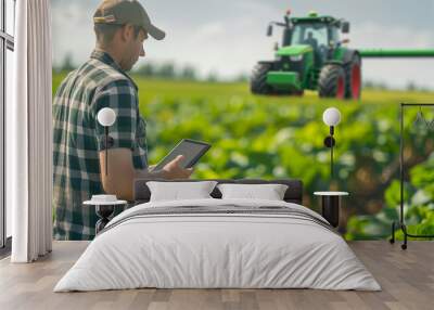 Farmer at a plantation field looking at a eletronic tablet Wall mural