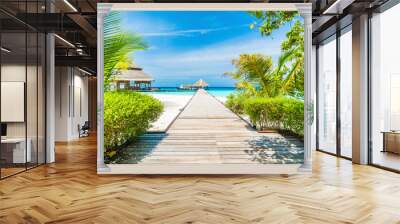 A wooden bridge leading across the ocean to the bungalow. Wall mural