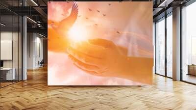 Woman praying with free bird,glittering light shine through hand women,who raise hands,to pray for God blessing,light and sunset background mind sanctification,concept pure spirit and spirituality Wall mural