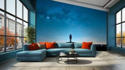 Silhouette of a man standing on top of a building and looking at the starry sky. Wall mural