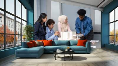 Architects engineers collaborating on building design project in modern office, diverse team of professionals female muslim architect and male engineers discussing architectural model of structure Wall mural