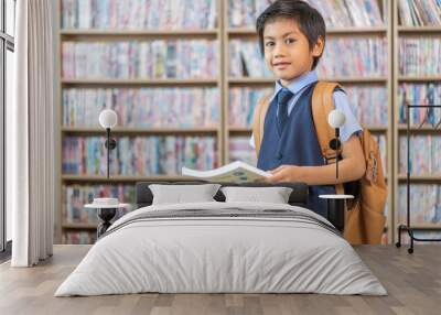 Cheerful of a young student asian boy carrying a backpack and smiling confidently at the camera standing joy and enthusiasm for learning in a library, education, school and academic achievement Wall mural