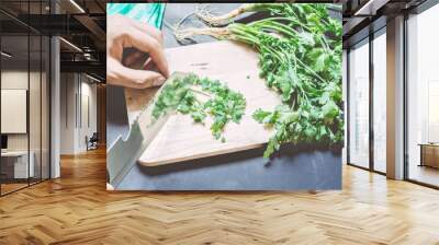 Chef chopping parsley leaves with a knife on a cutting board Wall mural