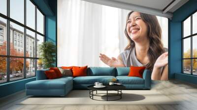 Excited asian woman expressing joy at home, cheerful and happy facial expression, positive emotions, surprised female reaction, happiness and delight, lifestyle, young woman celebrating good news Wall mural