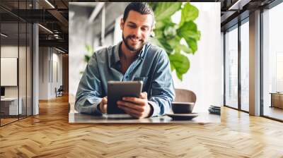 Handsome bearded hipster man relaxing using tablet computer while sitting on chair.technology and communication concept Wall mural