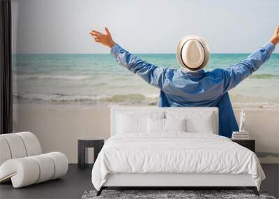 Handsome happy man relax breathing fresh air in straw hat sitting on the tropical beach and looking to the sea.Summer vacations Wall mural