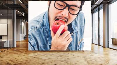 Handsome man eating and biting red apple. Healthy natural food concept Wall mural