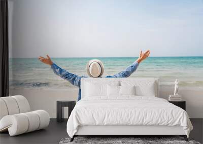 Handsome man relax in sunglasses and straw hat sitting on the tropical beach and looking to the sea.Summer vacations Wall mural