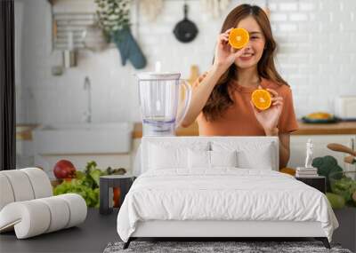 Portrait of beauty body slim healthy asian woman holding orange fruit slice hiding eye behind.young girl preparing cook healthy drink with orange juice in kitchen at home,Diet.Self love and Self care Wall mural