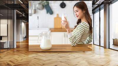 Portrait of beauty healthy asian woman smiling and having protein breakfast drinking and hold glasses of milk on counter in kitchen at home.Diet concept.healthy drink Wall mural