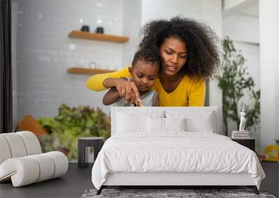 Portrait of enjoy happy love african american family mother and african little boy son child having fun help cooking food healthy eat together with fresh vegetable salad and ingredient in kitchen Wall mural