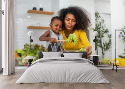 Portrait of enjoy happy love african american family mother and african little boy son child having fun help cooking food healthy eat together with fresh vegetable salad and ingredient in kitchen Wall mural