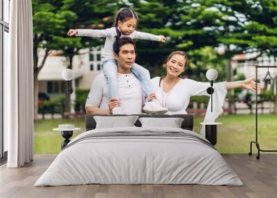 Portrait of enjoy happy love asian family father and mother holding cute little asian girl child smiling playing and having fun moments good time in summer park at home Wall mural