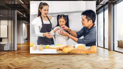 Portrait of enjoy happy love asian family father and mother with little asian girl daughter child play and having fun cooking food together with baking cookie and cake ingredient in kitchen Wall mural