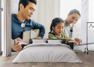 Portrait of enjoy happy love asian family mother and little asian girl child smiling and having fun teaching and play piano music lesson at home Wall mural