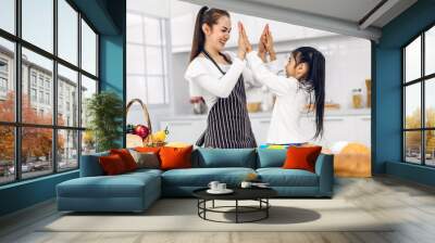 Portrait of enjoy happy love asian family mother and little asian girl daughter child having fun cooking together with baking cookies and cake ingredients on table in kitchen Wall mural