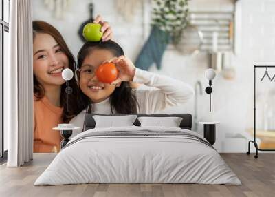 Portrait of enjoy happy love asian family mother and little asian girl daughter child having fun help cooking food healthy eat together with fresh vegetable salad and ingredient in kitchen Wall mural