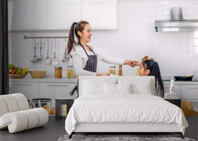 Portrait of enjoy happy love asian family mother and little toddler asian girl daughter child having fun cooking together with dough for homemade bake cookie and cake ingredient on table in kitchen Wall mural