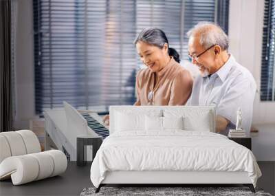 Portrait of enjoy happy love asian senior couple family having good time smiling and having fun play piano music lesson.Happy elderly husband and wife relax sitting on sofa at home Wall mural