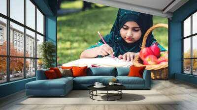 Portrait of happy little muslim girls child with hijab dress smiling and enjoy relax reading and write a book in summer park.Education concept Wall mural