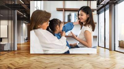 Portrait of happy love asian grandmother and asian little cute girl play and enjoy relax on bed at home.senior, insurance, care.Young girl with their laughing grandparents smiling together.Family Wall mural