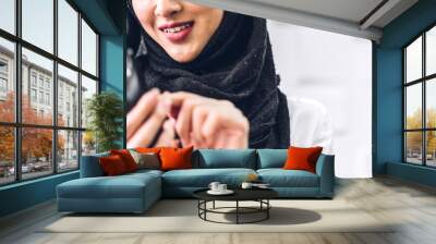 Portrait of smiling happy beautiful muslim woman relaxing using digital smartphone.Young muslim girl looking at screen typing message and playing game online or social media Wall mural