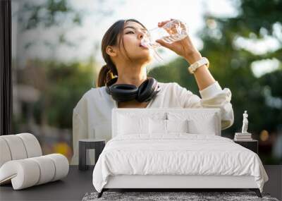 Portrait sport asian beauty body slim woman drinking water from a bottle while relax and feeling fresh,  refresh drink,  wellness, healthcare, mineral at green park.Healthy liquid lifestyle concept Wall mural