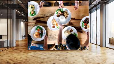 Top view of people having dinner together on wooden table Wall mural