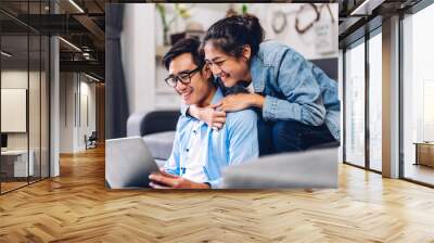 Young asian couple relaxing using laptop computer working and video conference meeting online chat.Creative business couple planning and brainstorm at home Wall mural