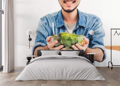 Young man eating organic healthy salad with vegetable in bowl on bed at home.diet food and healthy life concept Wall mural