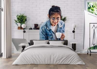 Young smiling happy asian woman relaxing using laptop computer working and video conference meeting online chat.Young creative girl look at business report paper at home.work from home concept Wall mural