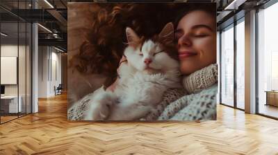 A woman with curly hair in a sweater sleeping on a bed hugging a cat, creating a warm and cozy home atmosphere. A close up portrait of the woman smiling happily, with soft lighting Wall mural