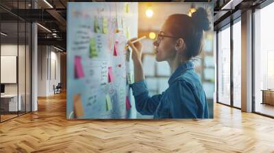 a young businesswoman writing on a whiteboard with sticky notes in her office, engaged in creative t Wall mural