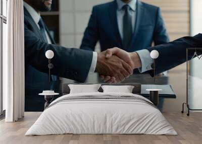 two individuals in formal attire shaking hands over a table with a document, symbolizing a professional agreement or partnership Wall mural