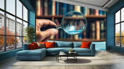 A hand holding a magnifying glass over financial graphs and reports in a library setting. Wall mural