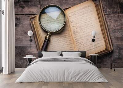 An open book with handwritten notes and a magnifying glass resting on its pages. Wall mural