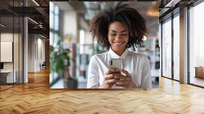 Portrait happy young african businesswoman using smartphone in the office Wall mural