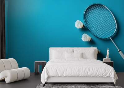 A badminton racket and shuttlecock resting on a blue background, ideal for sports enthusiasts Wall mural