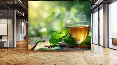 a cup of green tea next to mint leaves on a wooden table. blurred background of summer garden from behind Wall mural