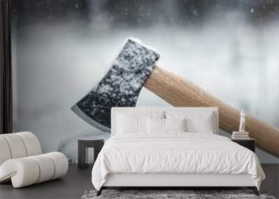 An axe resting on a snowy log during a tranquil winter snowfall in a forest setting Wall mural