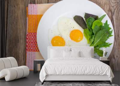 Breakfast. Fresh salad leaves and two fried eggs Wall mural