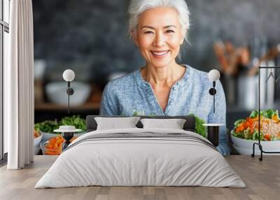 Elderly woman smiles, holding a large bowl of fresh veggies amid healthy ingredients Wall mural