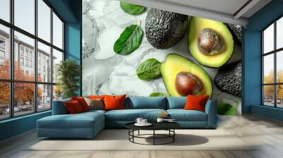 Fresh avocados with green leaves arranged on a smooth marble surface. Wall mural