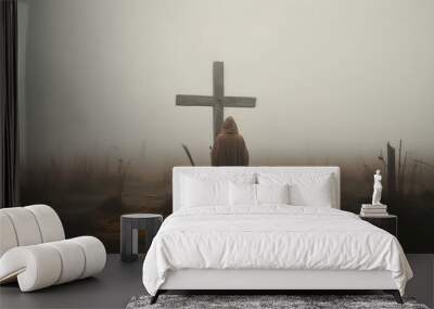 A faithful man in a cassock worships a large cross Wall mural